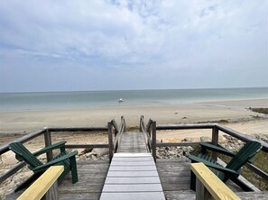 A wooden boardwalk leading to a beach with green Adirondack chairs. - Brewster Cape Cod Bay Waterfront (Brewster)