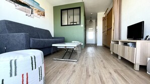 Uma sala de estar moderna com um sofá cinzento, uma mesinha e uma televisão sobre um armário de madeira.