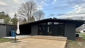 En modern uteplats med en pergola, ett garage och en klar himmel.
