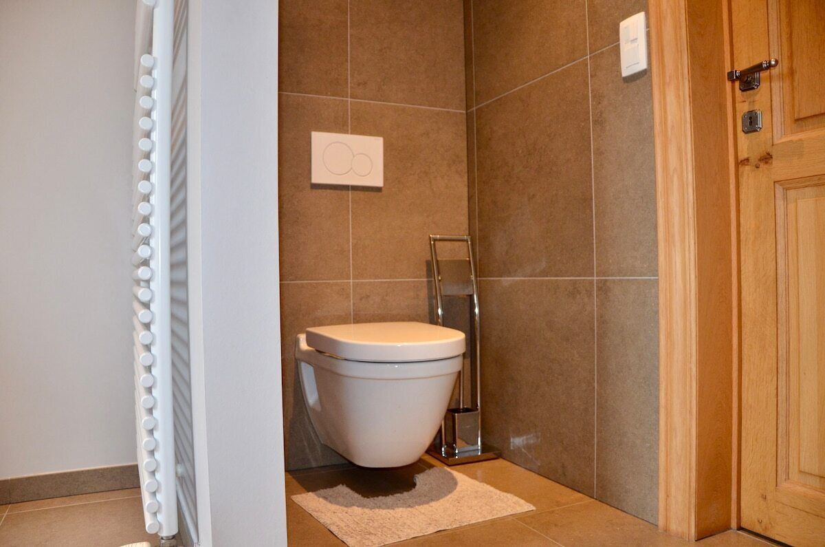 Une salle de bain avec des toilettes blanches, un rideau de douche et une porte en bois.