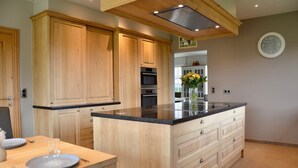 A modern kitchen with wooden cabinets, a central island, and a built-in oven.