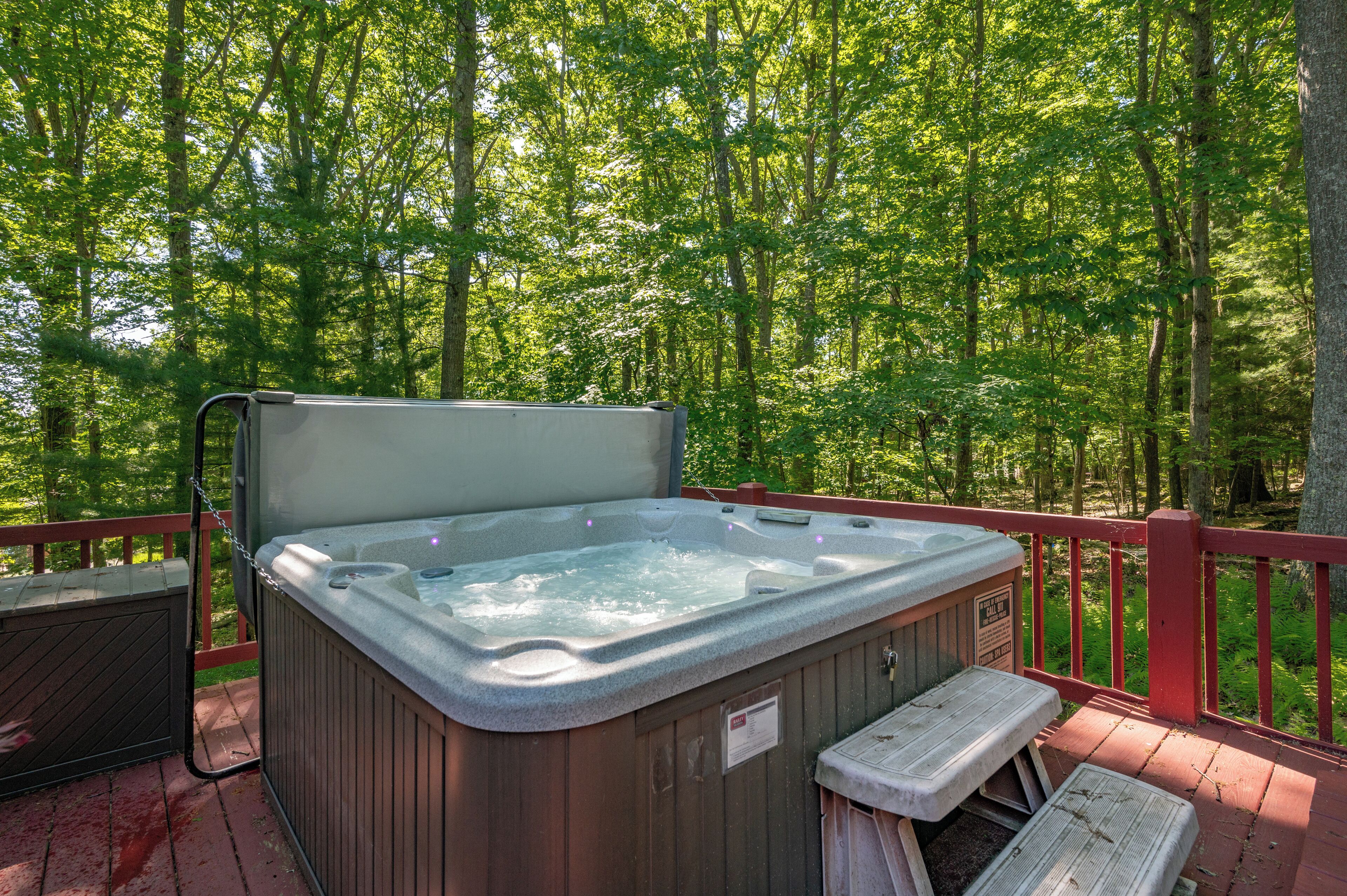 A hot tub on a wooden deck surrounded by a forest.