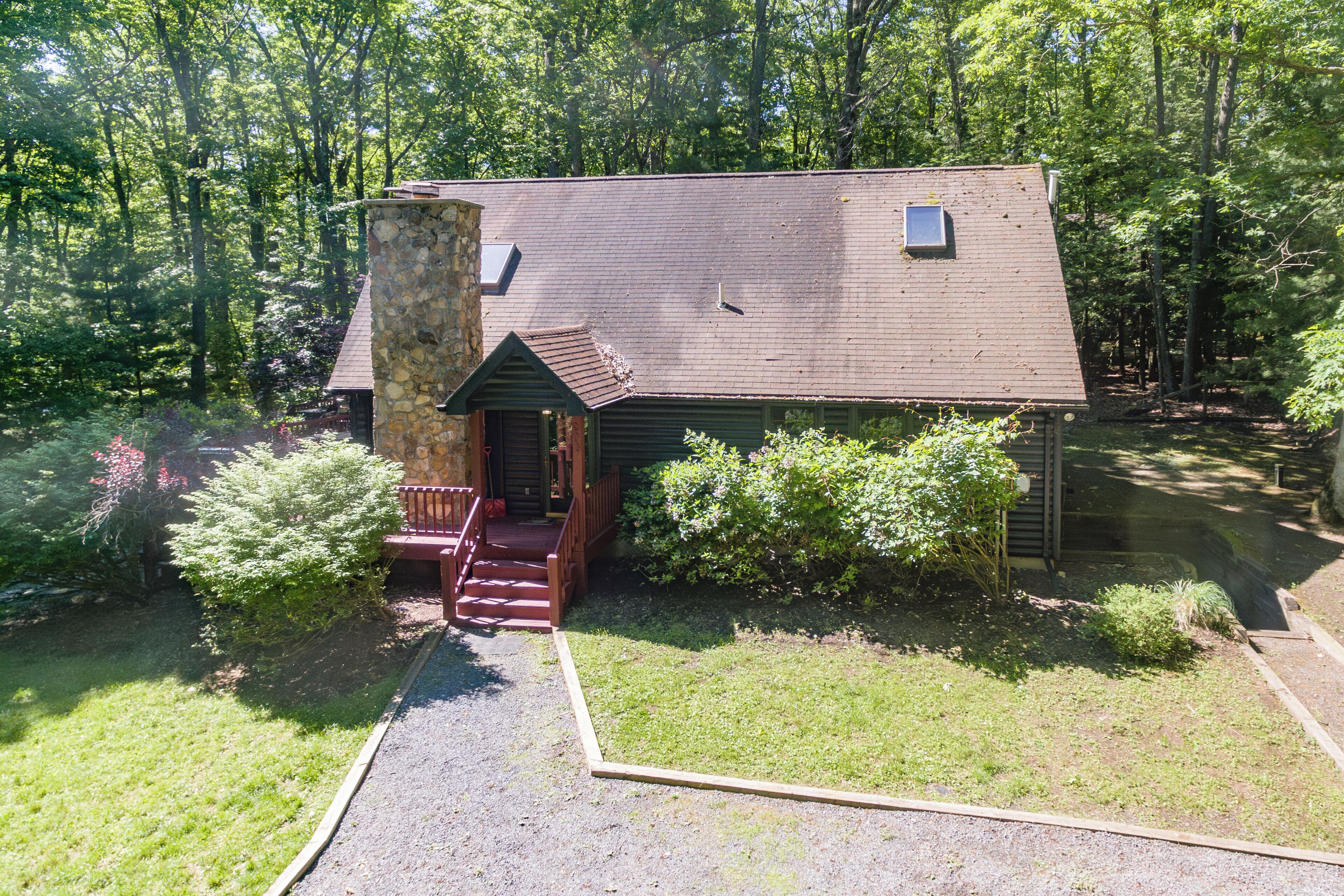 A rustic cabin with a stone chimney, a wooden porch, and a small window.