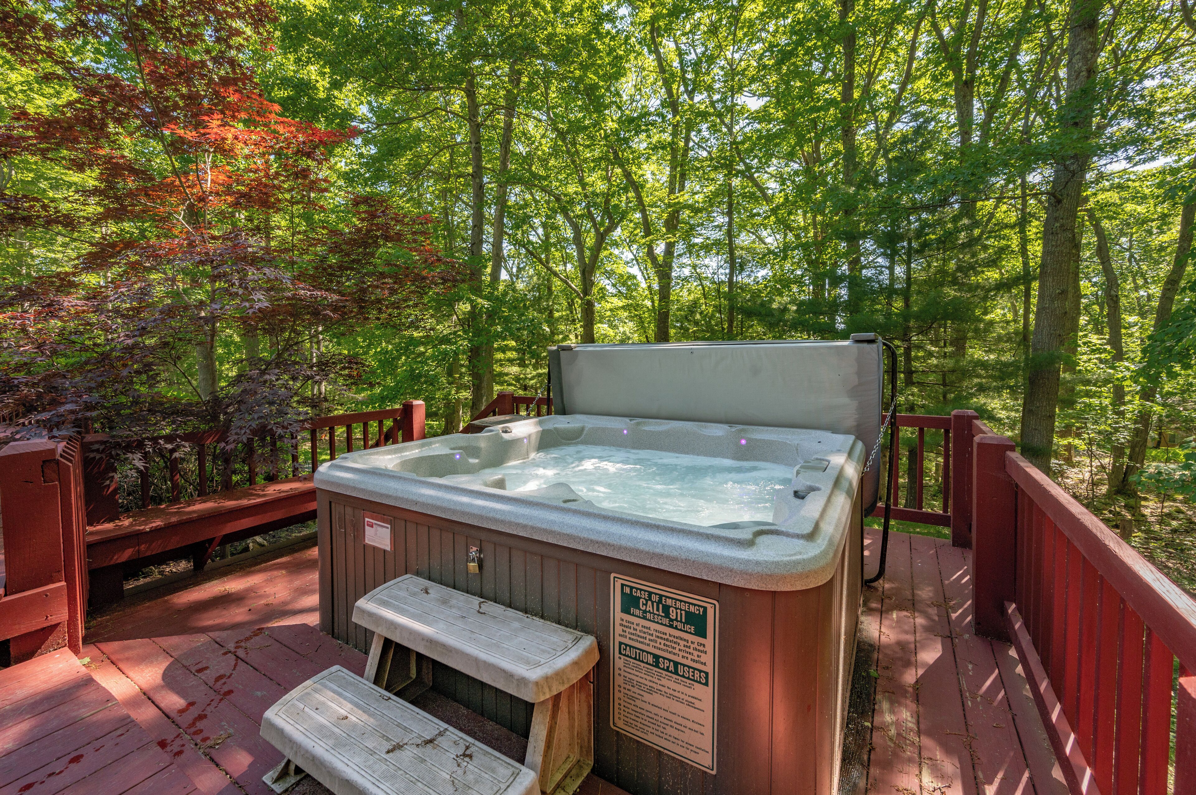 A hot tub on a wooden deck surrounded by trees.