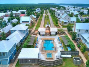 A residential area with a central swimming pool, houses with metal roofs, and a church with a steeple.