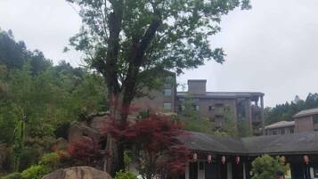 A building with a traditional architectural style, surrounded by lush greenery and large rocks.