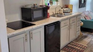 A compact kitchen with white cabinets, a microwave, a dishwasher, and a sink.
