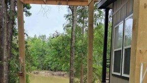 A hot tub in a covered outdoor area with a view of a pond and trees.