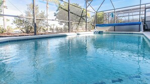 An indoor swimming pool with clear water, surrounded by a metal frame structure and trees in the background. - 'Morning Star Villa Spacious 4 bed with Salt Water Pool & Games Room! (Clermont)