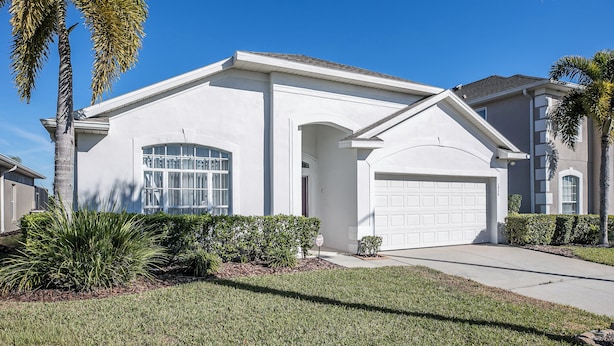 A single-story house with a white exterior, a garage, and a well-maintained lawn with palm trees. - 'Morning Star Villa Spacious 4 bed with Salt Water Pool & Games Room! (Clermont)