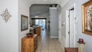 A hallway with a wooden dresser, a mirror, and a door leading to a kitchen. - 'Morning Star Villa Spacious 4 bed with Salt Water Pool & Games Room! (Clermont)