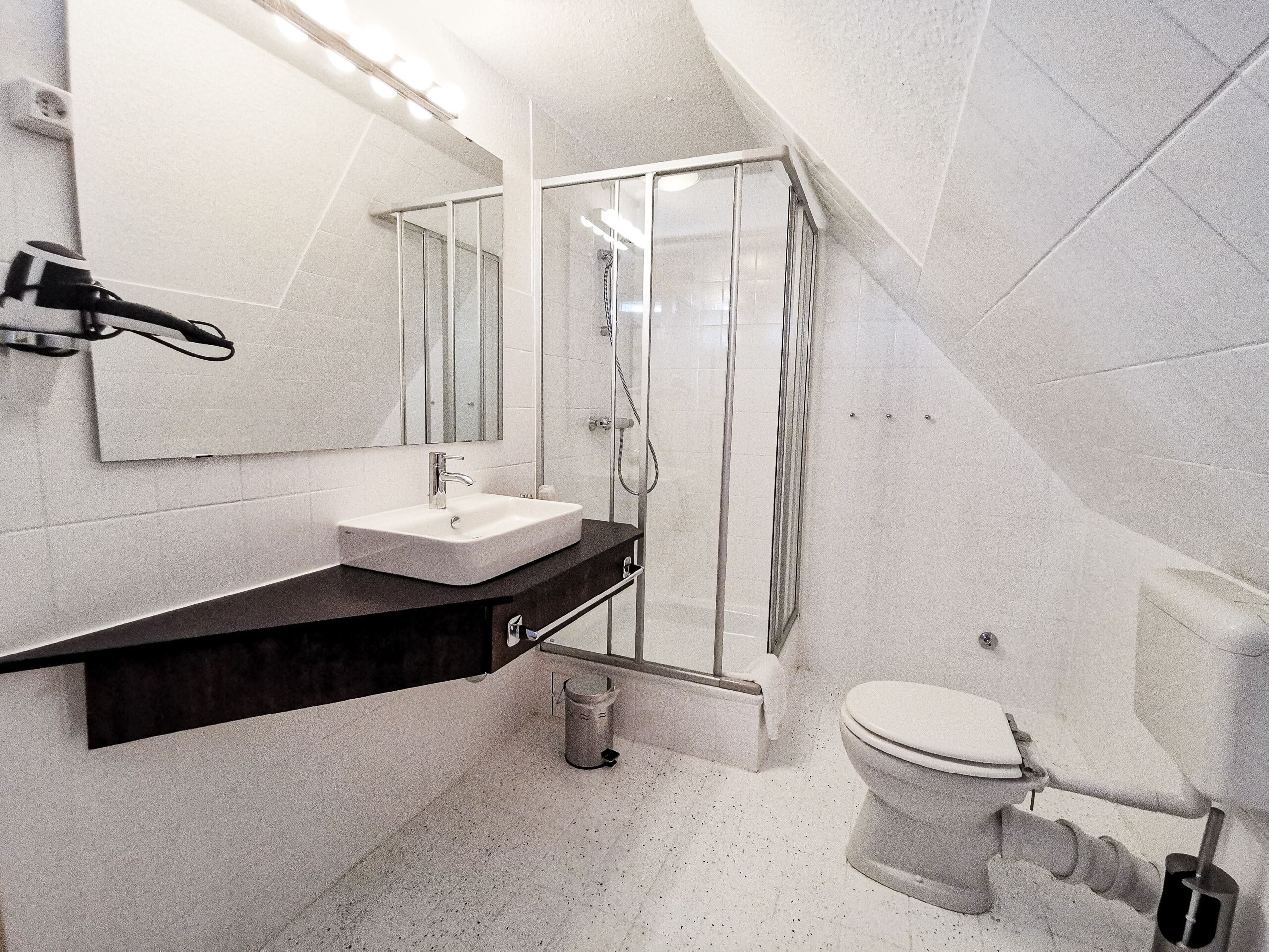 Ein modernes Badezimmer mit Waschbecken, Spiegel und Dusche.
