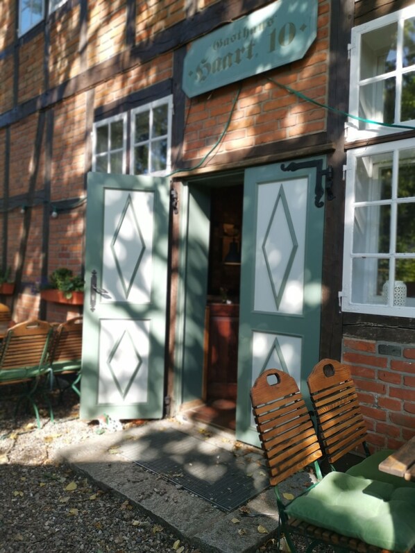 A building with a sign reading "Saarl", a wooden door, and two wooden chairs outside. - Kontraste (Neumuenster)