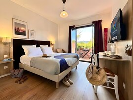 Quarto de hotel com cama, mesa de cabeceira, luminária e vista para o exterior.