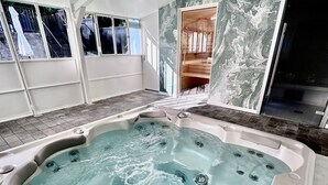 A modern spa room with a large hot tub, marble walls, and large windows. - Hotel Le Provence - Restaurant Le Styx (La Palud-sur-Verdon)