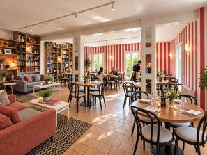 A spacious living area with a sofa, coffee table, and bookshelves filled with books and decorative items. - Hotel Le Provence - Restaurant Le Styx (La Palud-sur-Verdon)