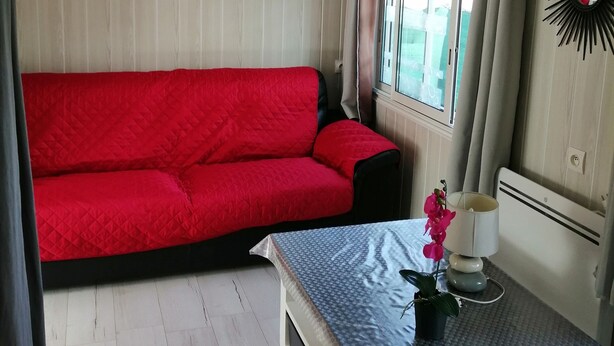 A compact living space with a red sofa, a small table with a lamp, and a decorative mirror. - 2-BEDROOM CHALET IN SUNNY PROVENCE (LE CASTELLET)