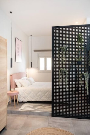 A bedroom with a bed, bedside table, and a decorative black partition with plants. - Casa d oro 56 Living in Paradisi Rhodes (Rhodes)