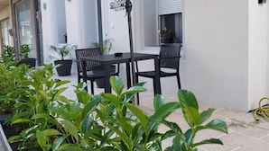 Une terrasse extérieure avec une table et des chaises, entourée de plantes en pot.