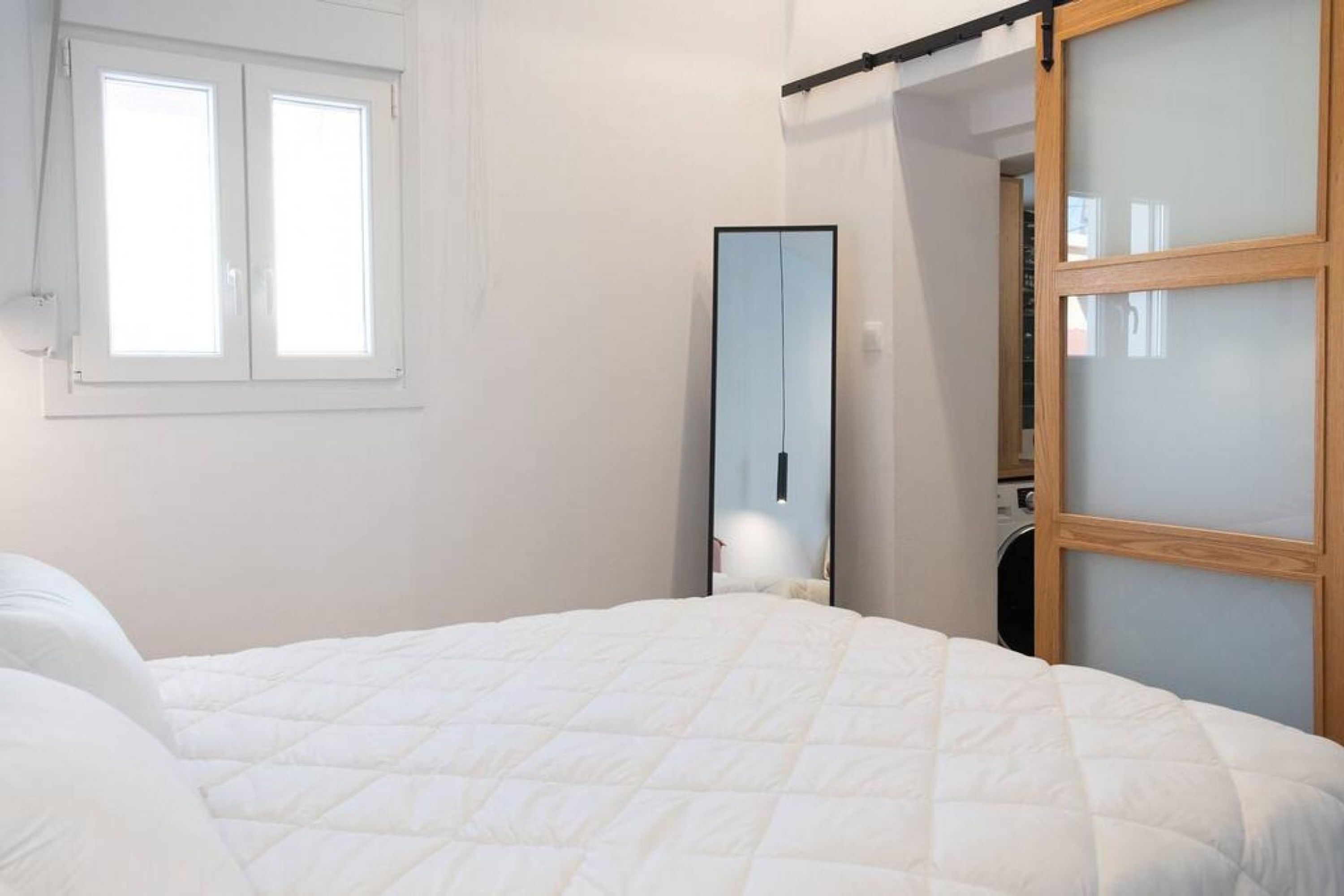 A bedroom with a bed, a wardrobe, and a window.