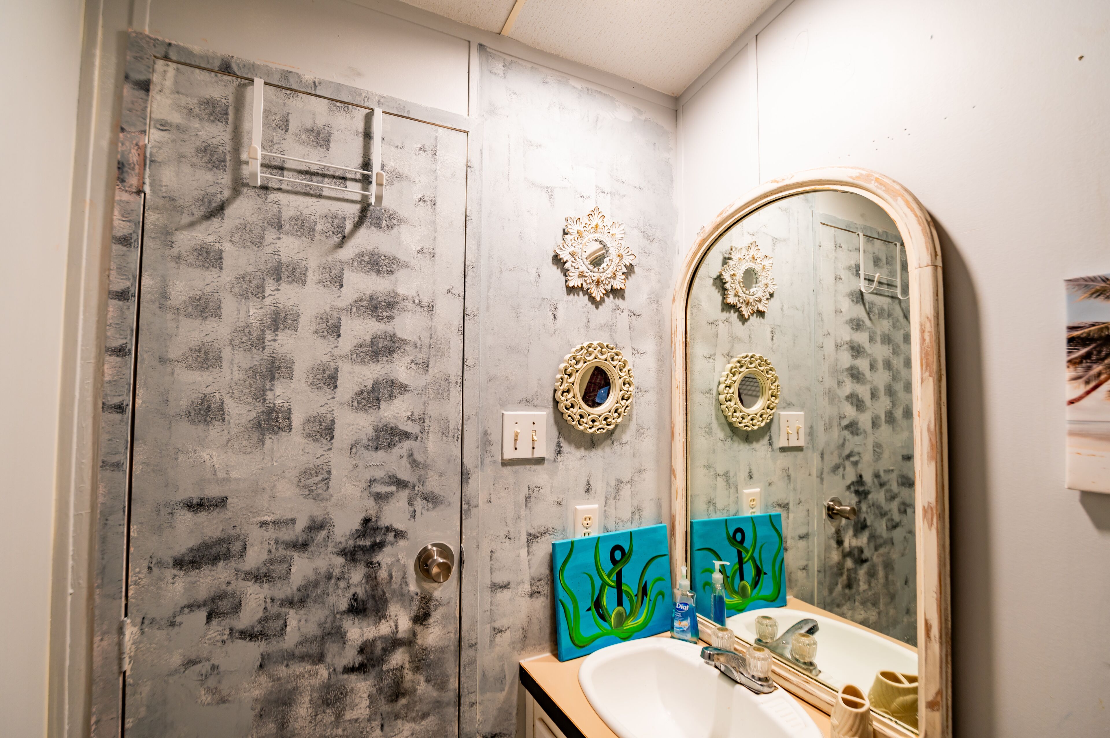 A bathroom with a large mirror, a sink, and a shower.