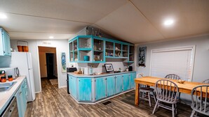 Eine Küche mit Holzboden, einem Esstisch mit Stühlen und einem blauen Schrank mit Gläsern.