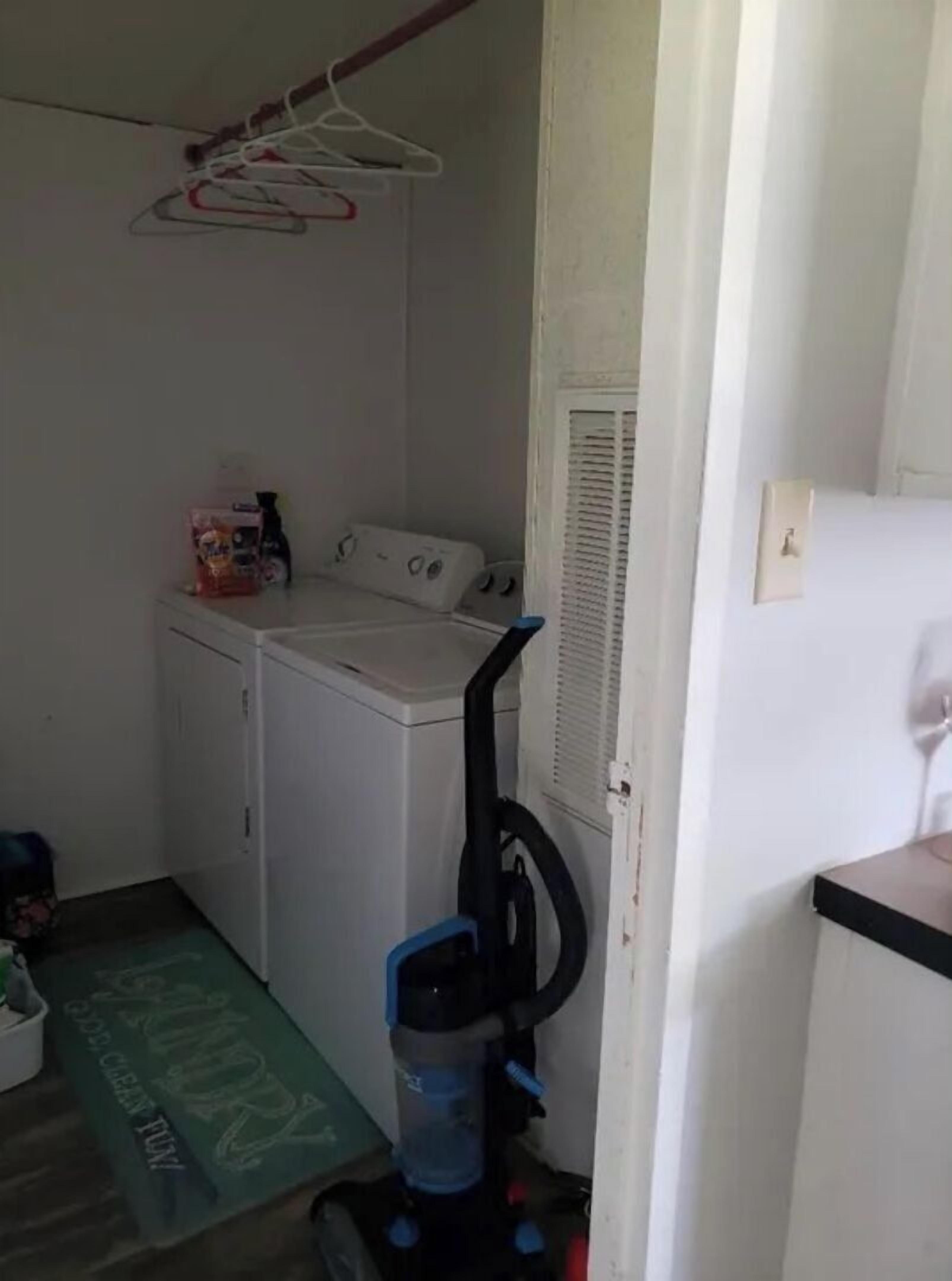 A laundry room with a washing machine, dryer, and a vacuum cleaner.