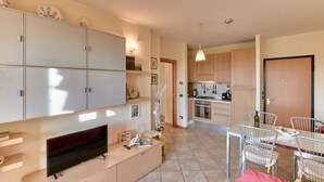 Una cocina moderna con armarios de madera, un comedor con mesa y sillas, y un televisor sobre un mueble de madera.
