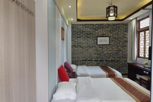 Habitación de hotel con dos camas, pared de ladrillo, escritorio y ventana con cortinas.