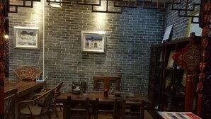 Comedor con pared de ladrillo, mobiliario de madera y cuadros enmarcados.