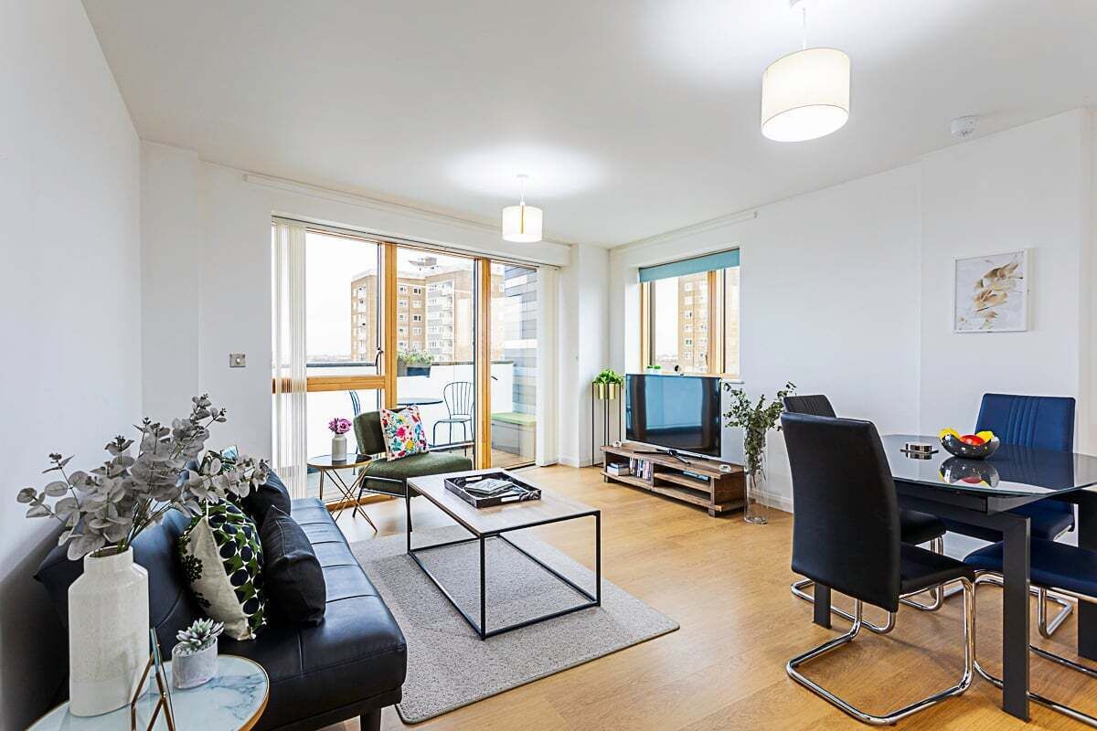 A modern living room with a sofa, coffee table, TV, and dining area.