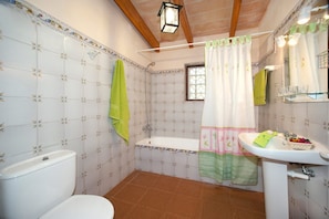 Bathroom features a classic design with a bathtub, toilet, and sink, adorned with a floral tile pattern and a window above the bathtub.