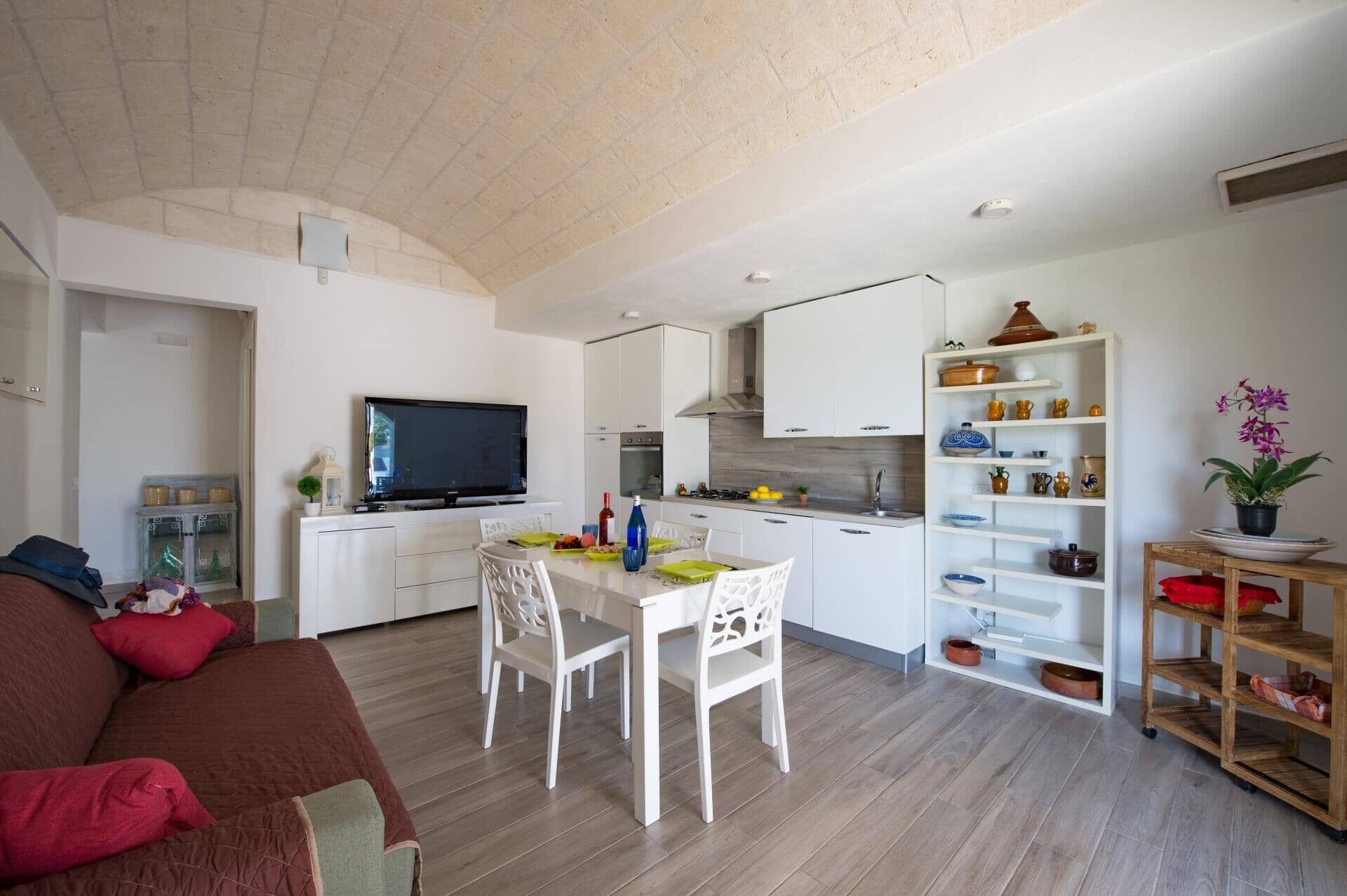 Un espacio habitable compacto con kitchenette, comedor y televisor.