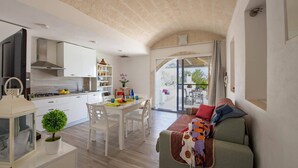A modern kitchen with white cabinets, a dining area with a table and chairs, and a cozy living space with a sofa.