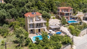 Ein mehrstöckiges Gebäude mit Pool, umgeben von Grünflächen und Hügeln.