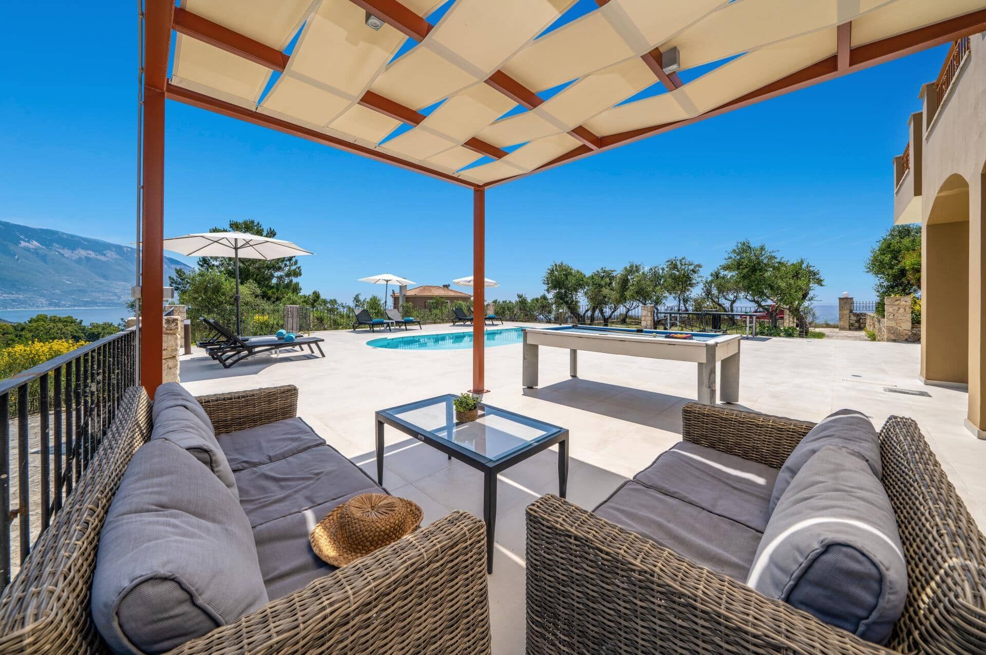 An outdoor seating area with wicker furniture, a pool table, and umbrellas.