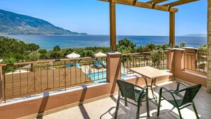 Un balcón con piscina, mobiliario exterior y vistas al mar y a las montañas.