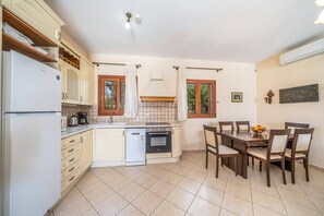 A compact kitchen with a refrigerator, stove, and dishwasher. There is a dining area with a table and chairs.