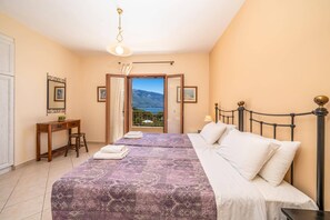 Quarto com cama, escrivaninha e vista para o mar.