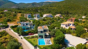 Oversigtsbillede af et resort med villaer, der hedder Villa Roses og Villa Rubi, omgivet af frodig vegetation og bjerge.