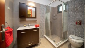 Une salle de bain moderne avec une douche à parois de verre, un meuble-lavabo avec un miroir et des toilettes.