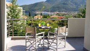 Un balcon avec une table et des chaises, une vue sur un lac et des montagnes en arrière-plan.