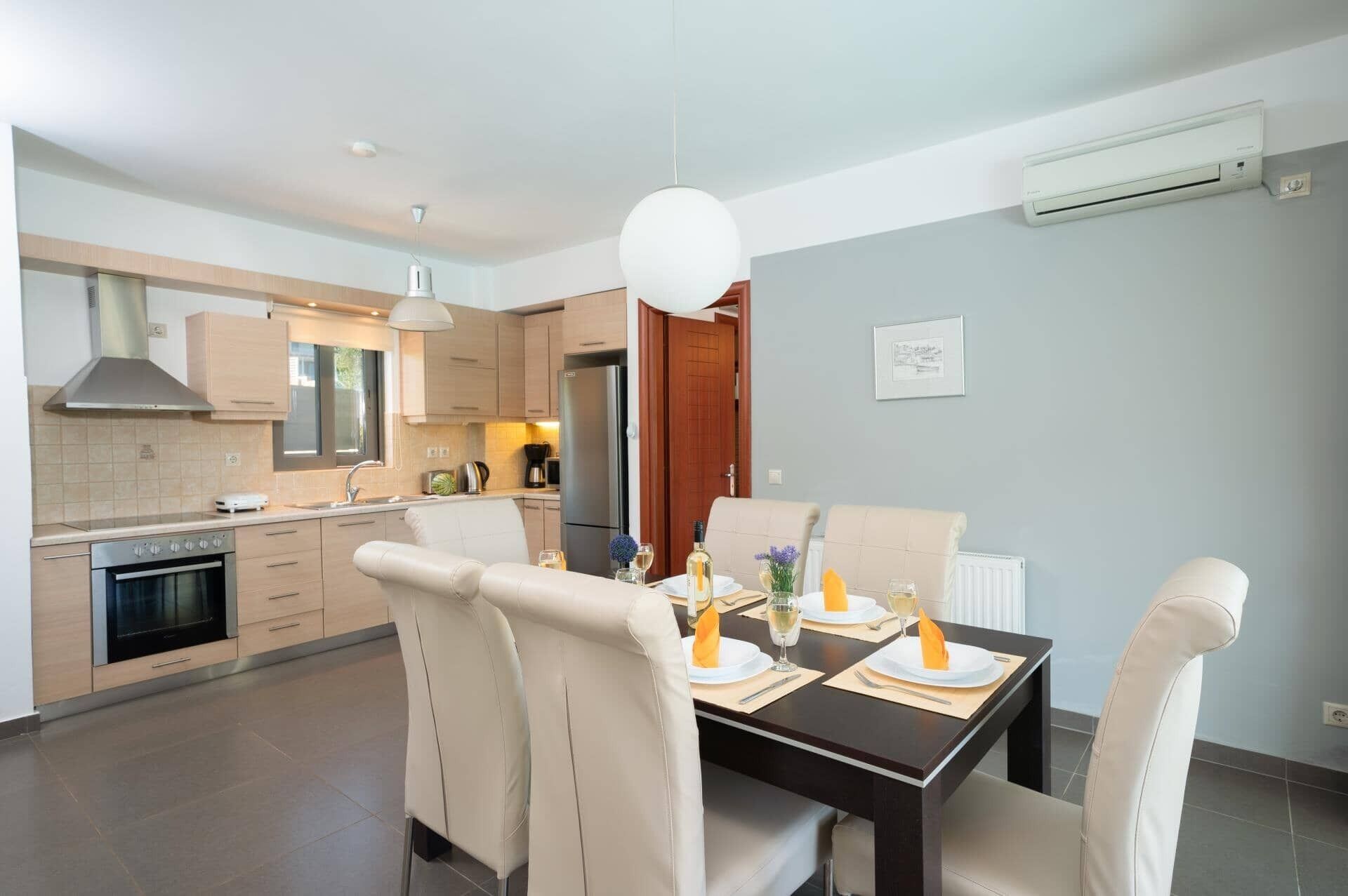 Una cocina moderna con comedor, que incluye un horno empotrado, un refrigerador y una mesa de comedor lista para cuatro personas.