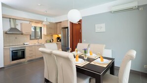 Une cuisine moderne avec un coin repas, comprenant un four encastré, un réfrigérateur et une table à manger pour quatre personnes.