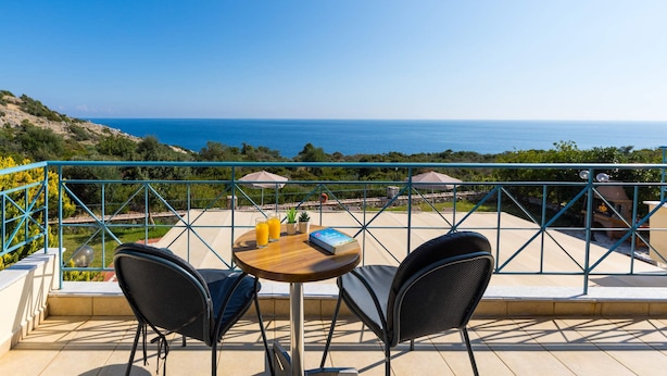 A balcony with two chairs and a table, overlooking a coastal view. - Villa Skala Ionian by Villa Plus (Ionian Islands)