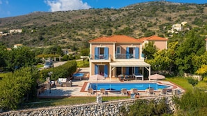 A two-story house with a swimming pool, outdoor furniture, and a view of the surrounding hills. - Villa Skala Ionian by Villa Plus (Ionian Islands)