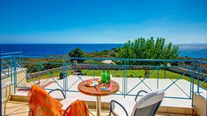 Uma varanda com mesa, cadeiras e vista para o mar.