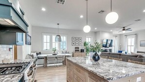 A modern kitchen with a large island, wooden cabinets, and a dining area with a table and chairs.