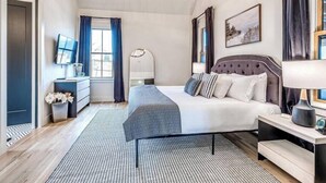 A bedroom with a bed, bedside table, lamp, and a window with curtains.