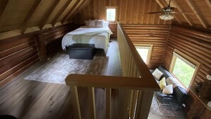 Ein Schlafzimmer im Loft-Stil mit schrägverdeckter Holzwand, einem Bett, einer Sitzecke und einem kleinen Fenster.